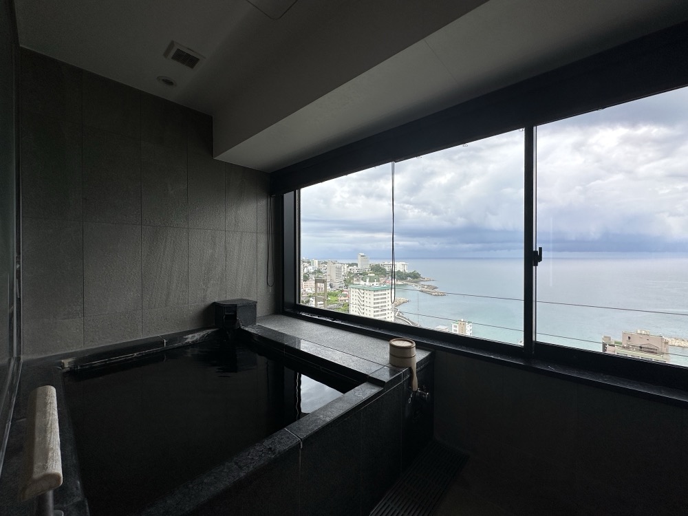 部屋の温泉。窓の外に街と海が見える