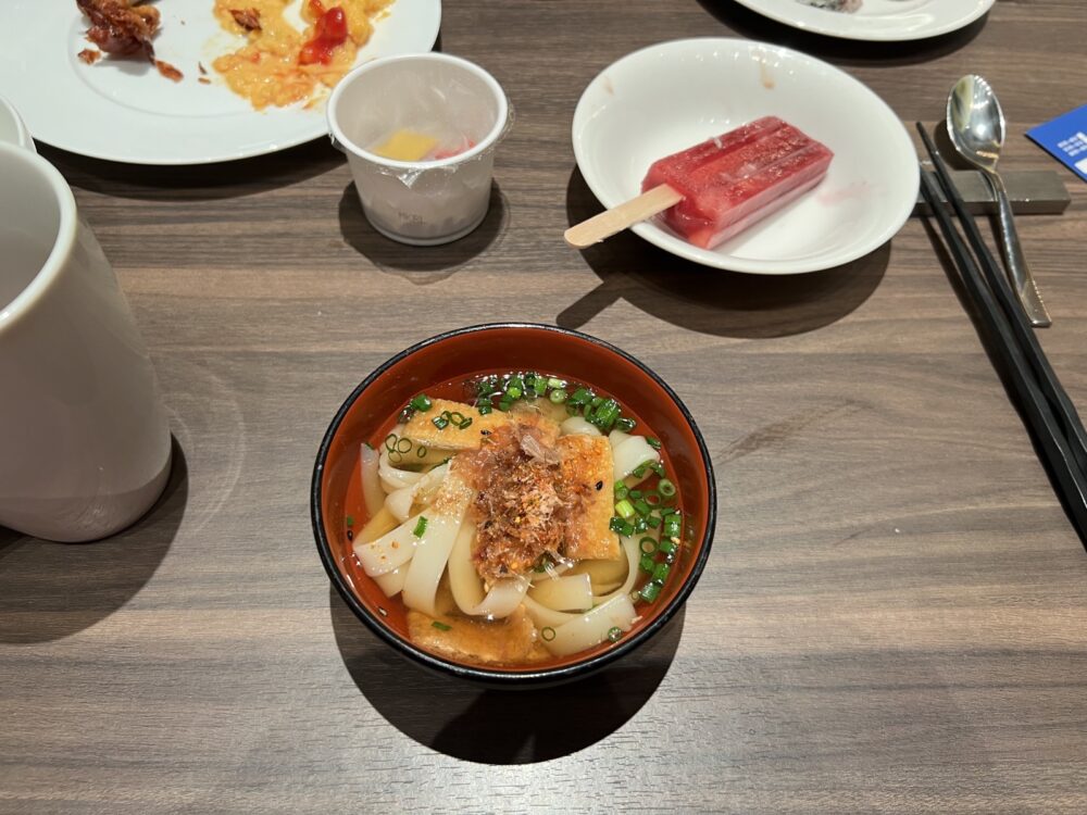 きしめん。赤だしの汁に平たい麺、油揚げと鰹節、青ねぎ