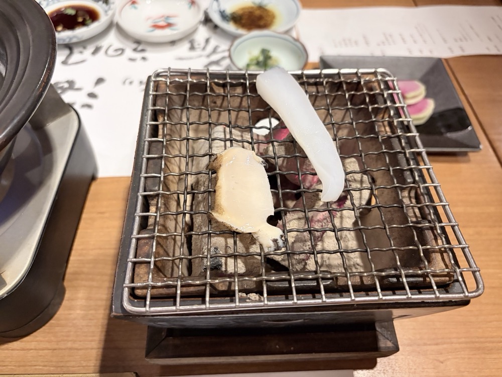 黒鮑と烏賊を、炭火の網に載せます