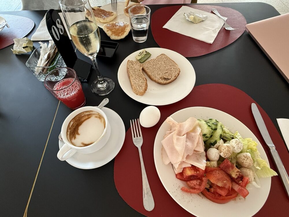 朝食のプレート。カプチーノとスパークリングを並べて