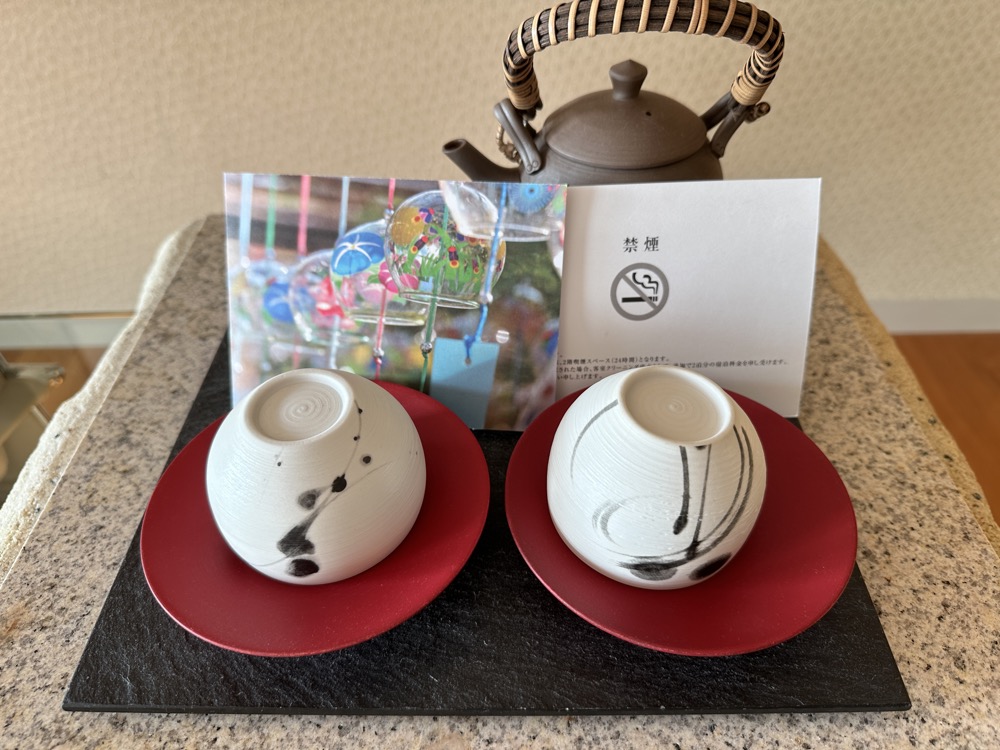 お茶のセットです。急須と、筆で描いたような湯呑が2つ。赤い漆の茶托にのっています