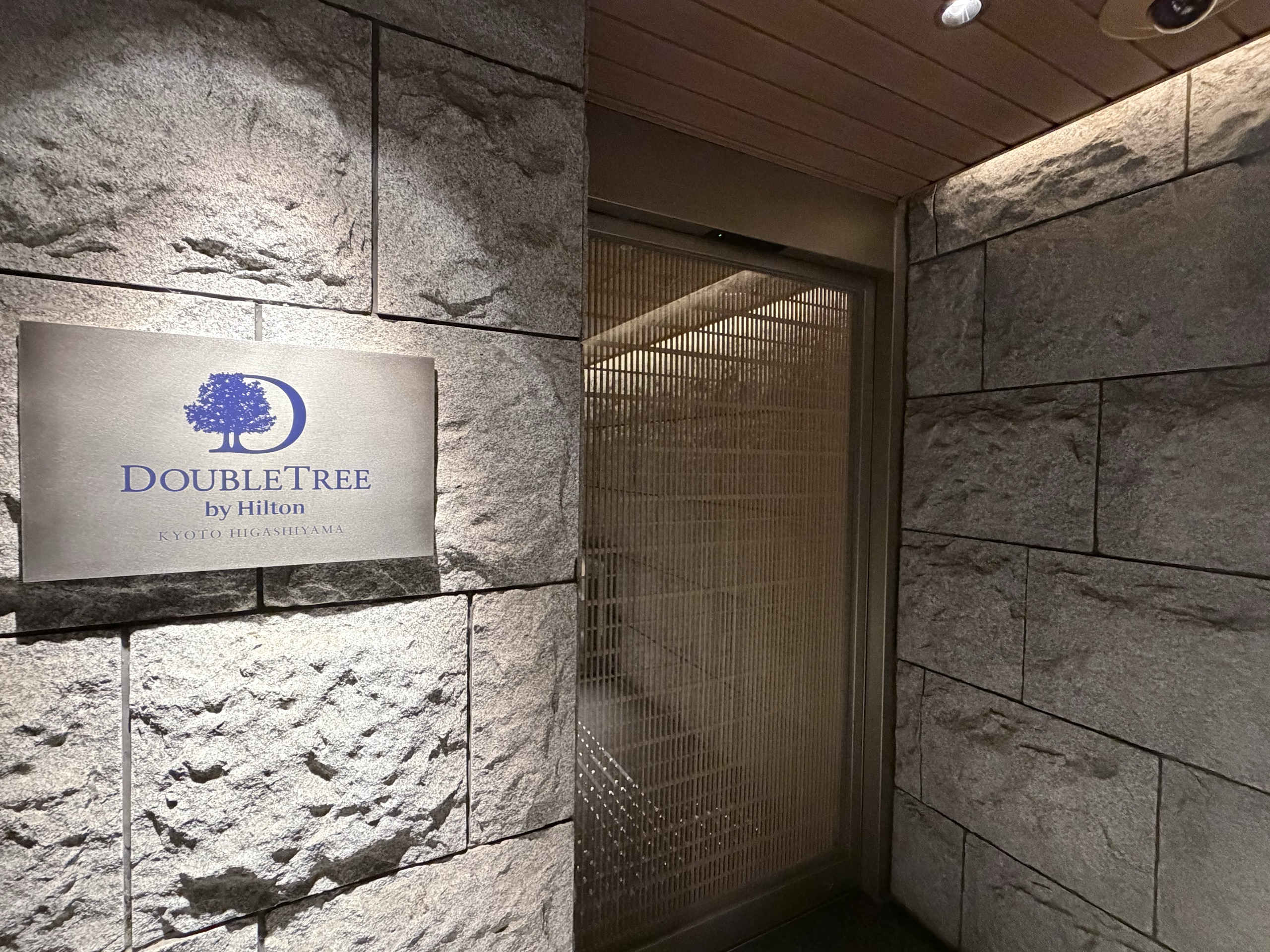ダブルツリー京都東山の入口の石の壁に付いた、ホテルの名前の金属の看板