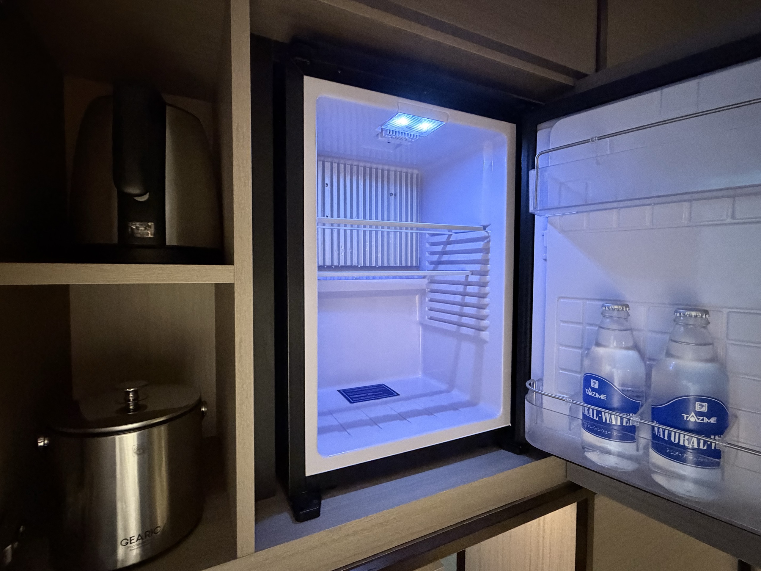 扉を開けた冷蔵庫と、上の棚の電気ケトル
