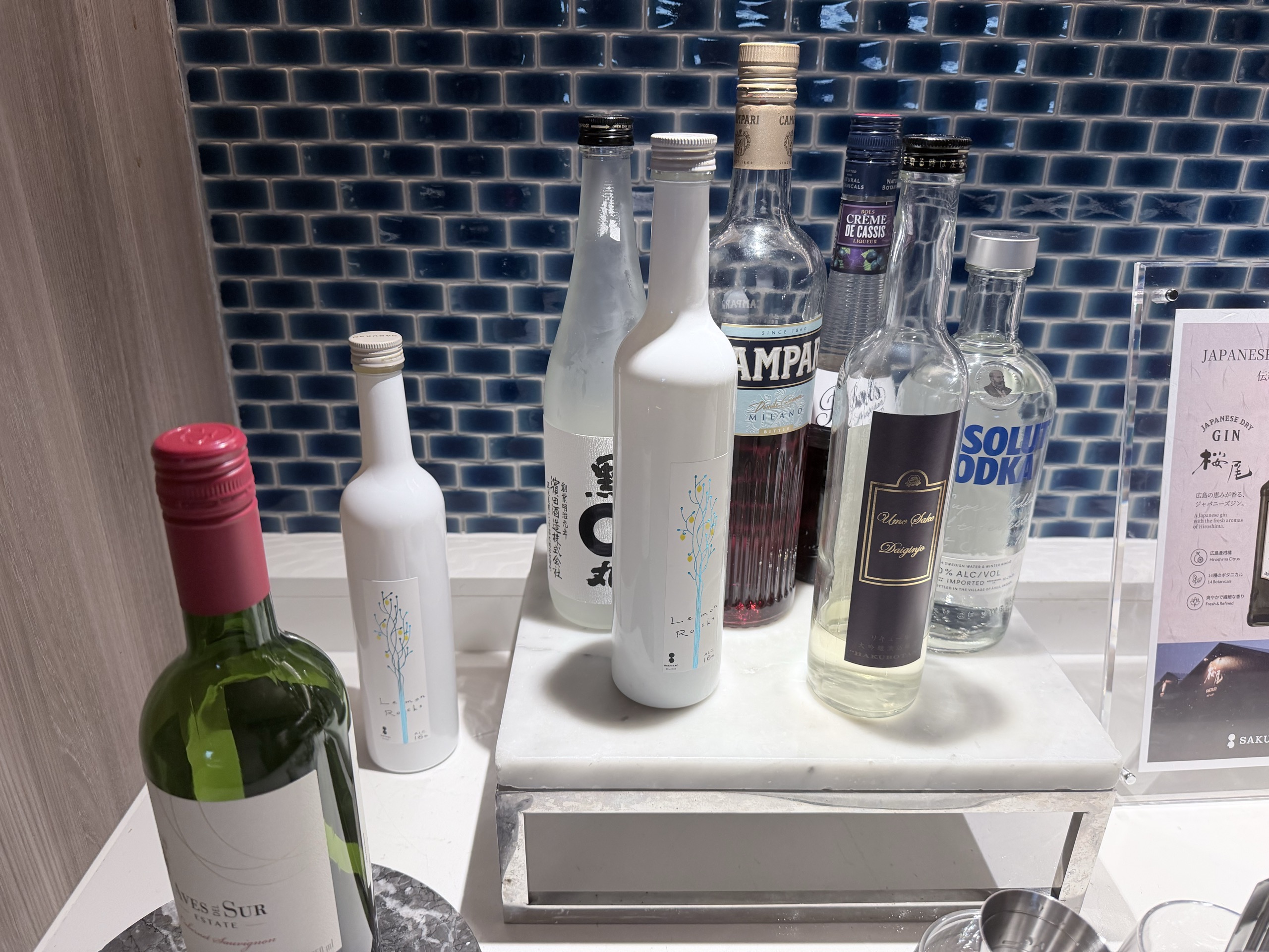 青いタイルの壁の前に並んだ酒のびん