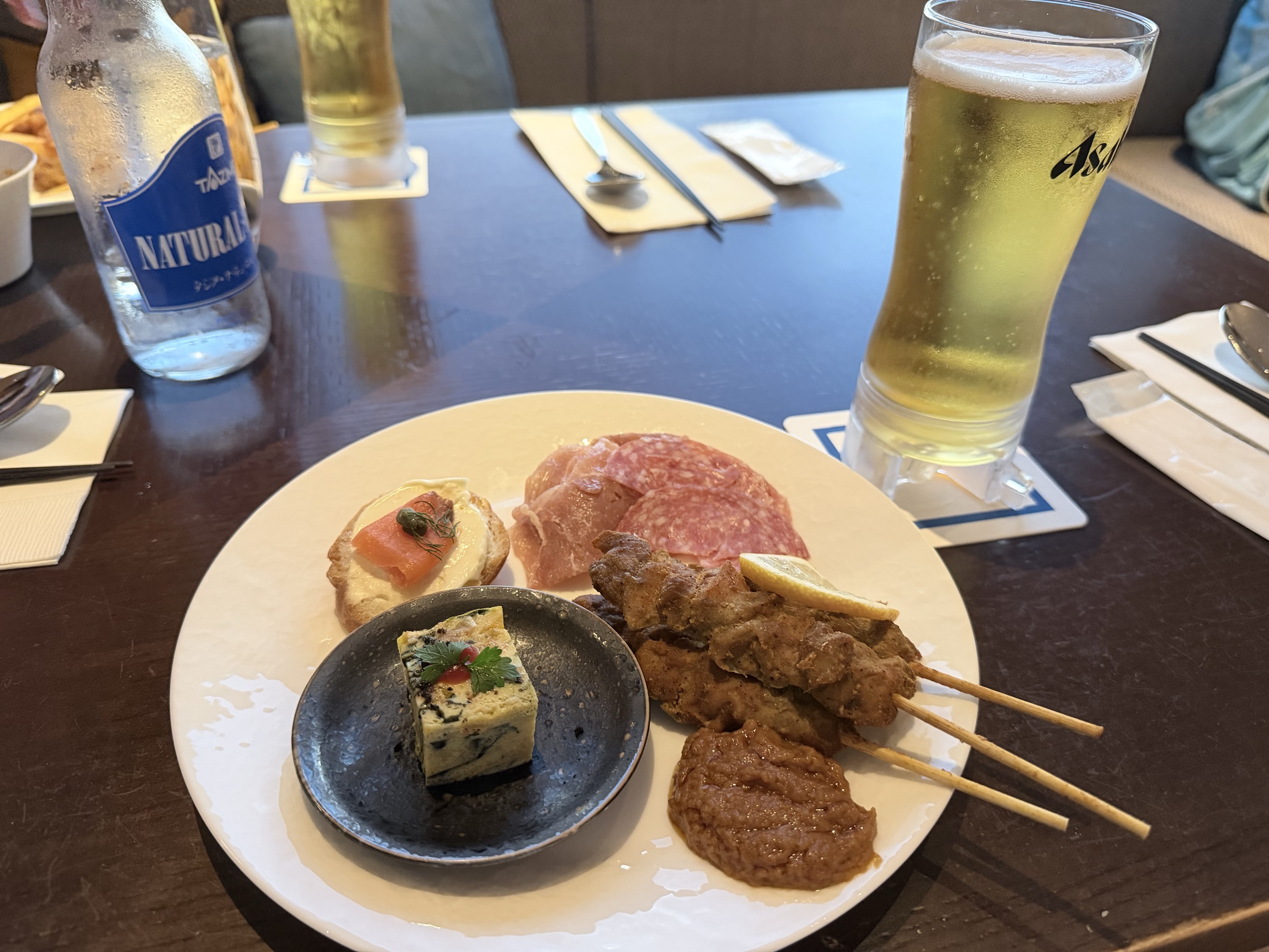 ラウンジで取り分けた、ブルスケッタとハム、チキンサテ串などのお皿