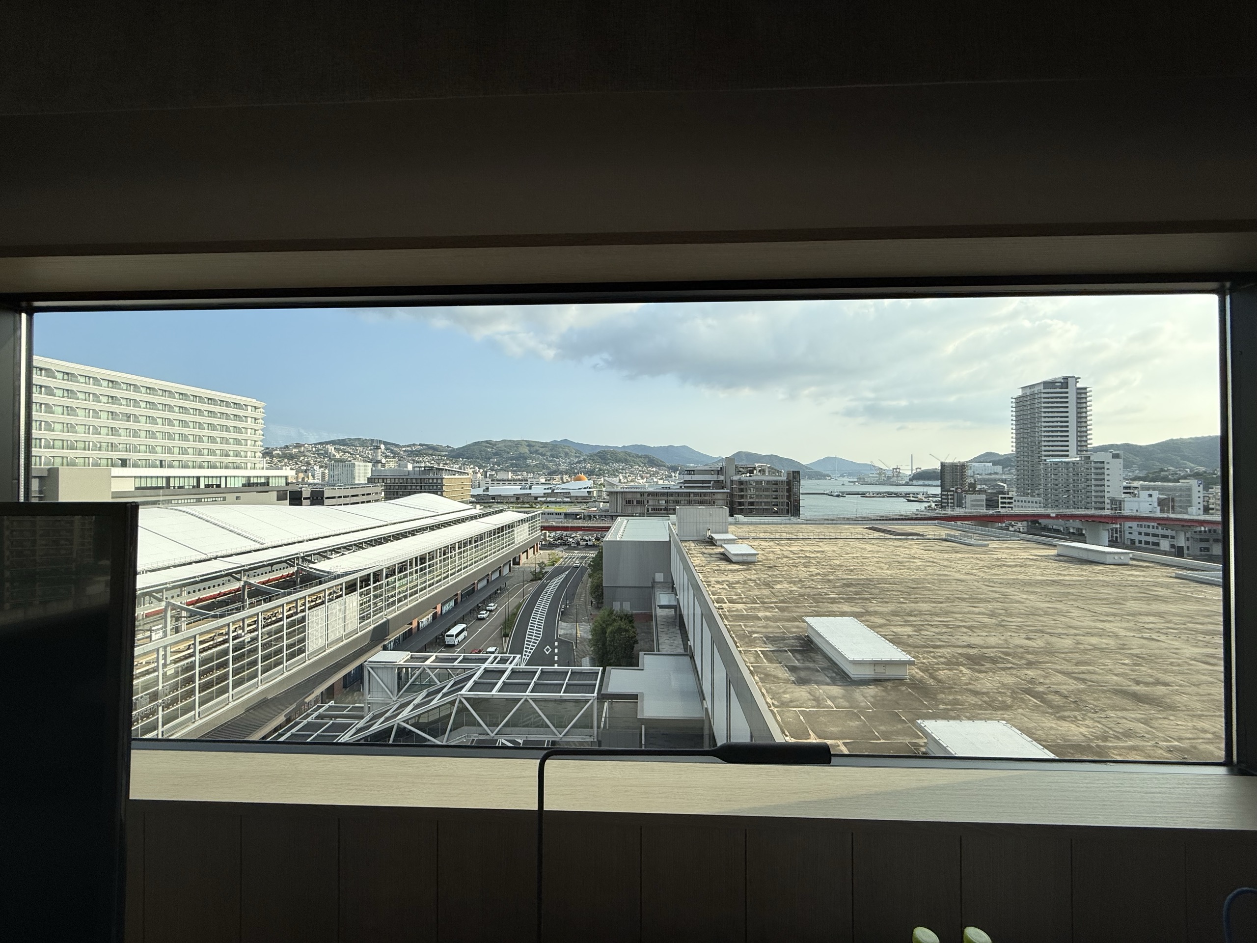 机の前の窓から見える、駅と線路、港と山並み