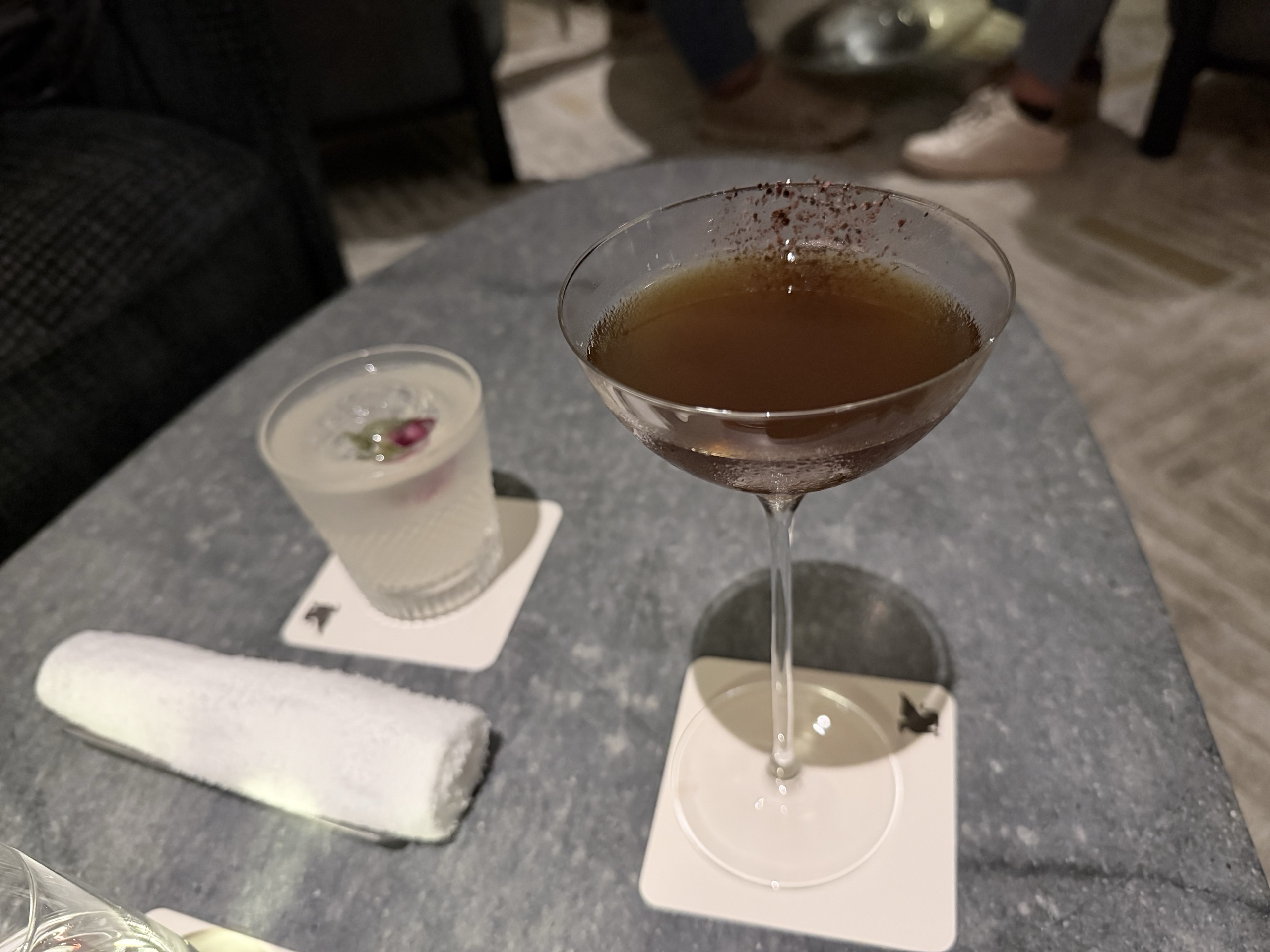 縁に粉をちらした茶色のカクテルと、バラの蕾を浮かべた白いカクテル