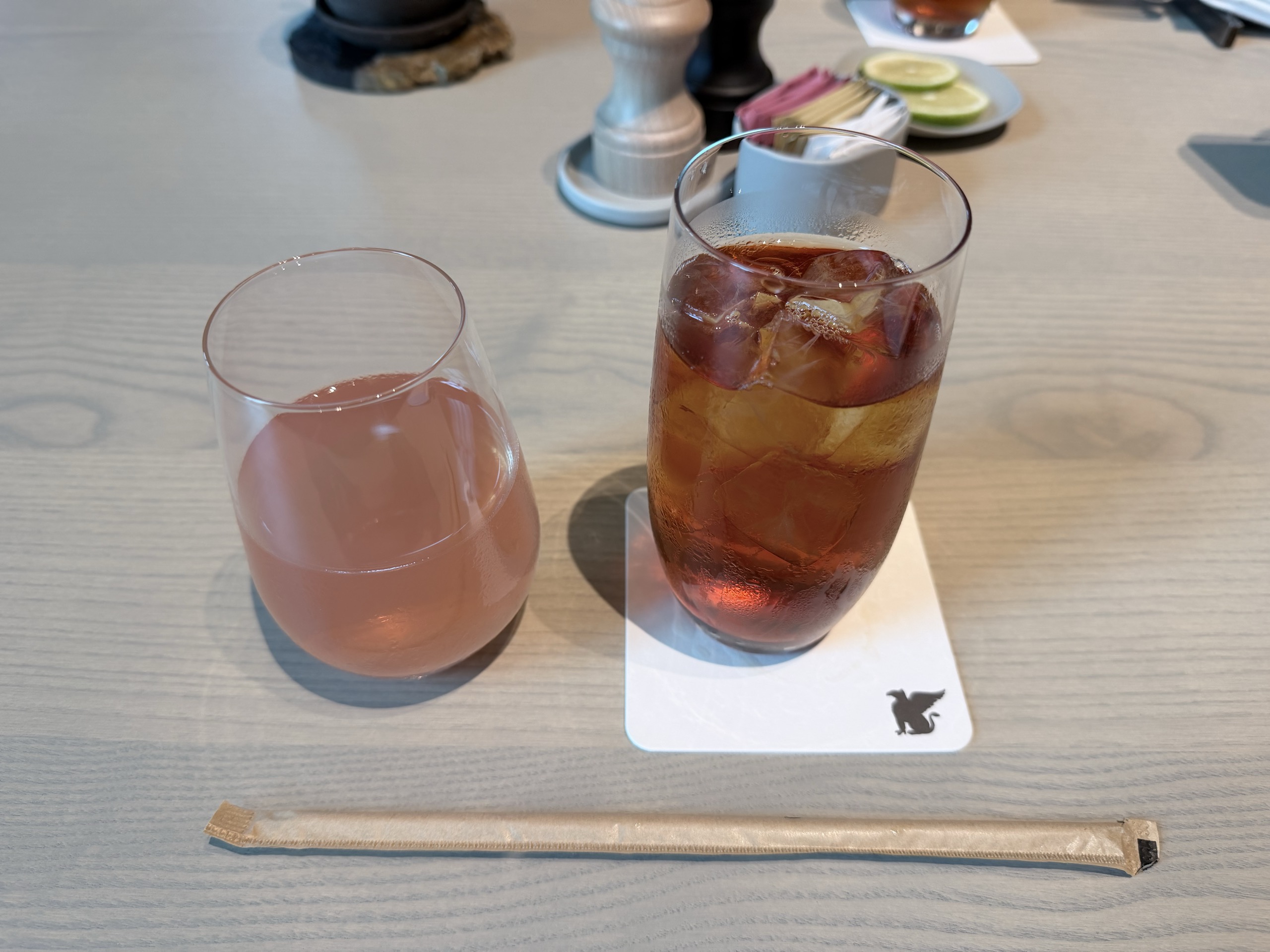 ピンク色の飲み物と、氷の入った茶色の飲み物が並ぶ朝食の席