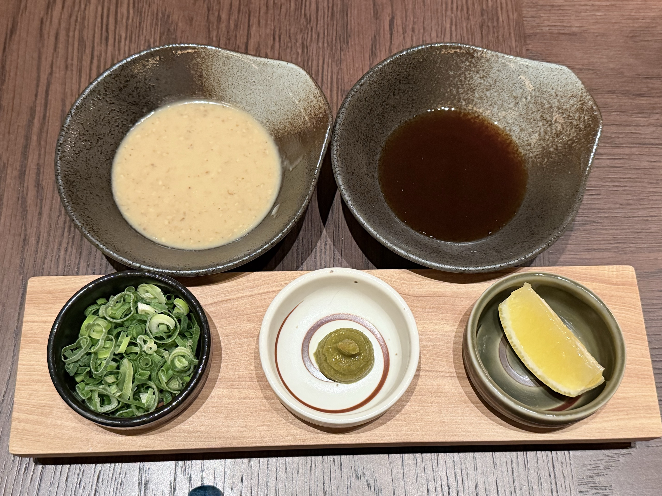 シークワーサーポン酢とごまだれが入った器2つと、小皿3つをのせた木の板