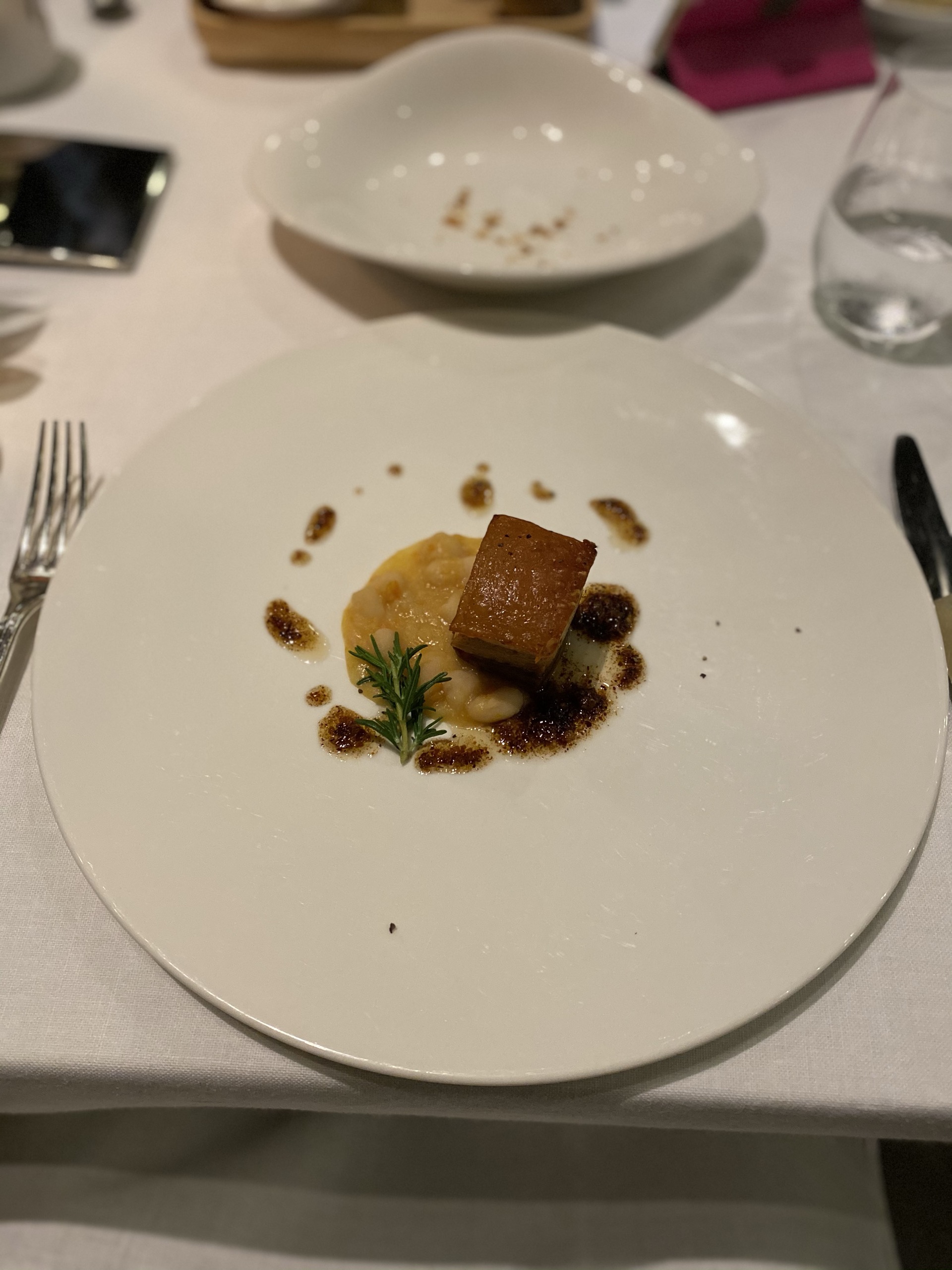 白い大皿に盛られた、角切りの焼いたお肉と豆のペーストとローズマリー